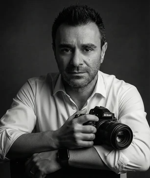 Retrato en blanco y negro de Rubén Casado sujetando una cámara de fotos. Fotógrafo de moda en Valladolid.